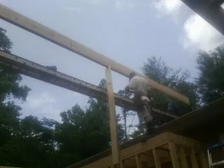 Carpenter setting a ridge beam over a new addition frame — Ice Dam Removal by Roofing Brothers in Spotswood