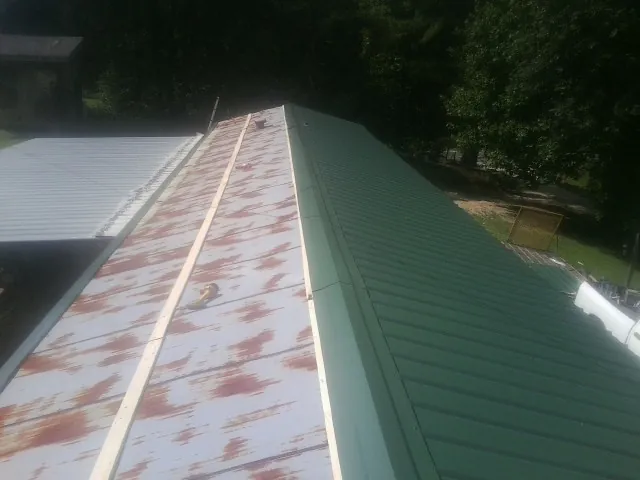 Old rusted panels beside newly installed green metal roofing — Wind Damage Roof Repair by Roofing Brothers in Spotswood