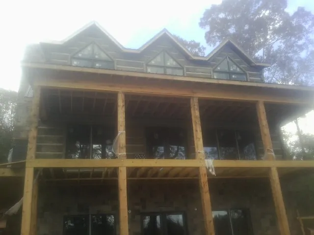 Dormers and porch framing on a large log home under construction — Roof Coating work by our crew in Spotswood