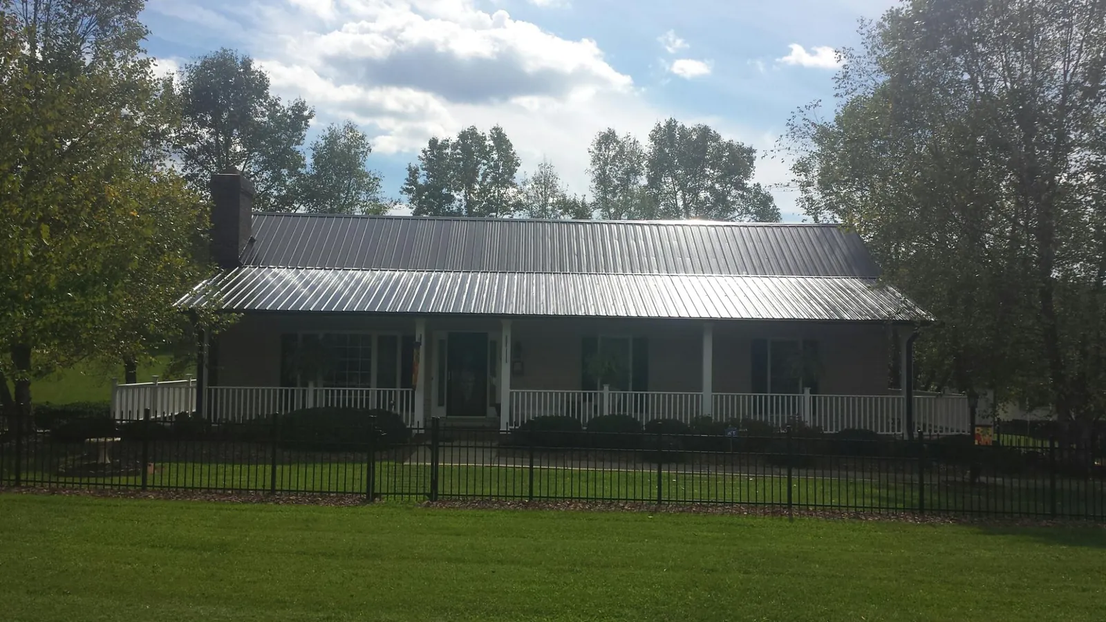 Gray metal roof on a brick ranch with a full width front porch — Gutter Guard Installation work by our crew in Spotswood
