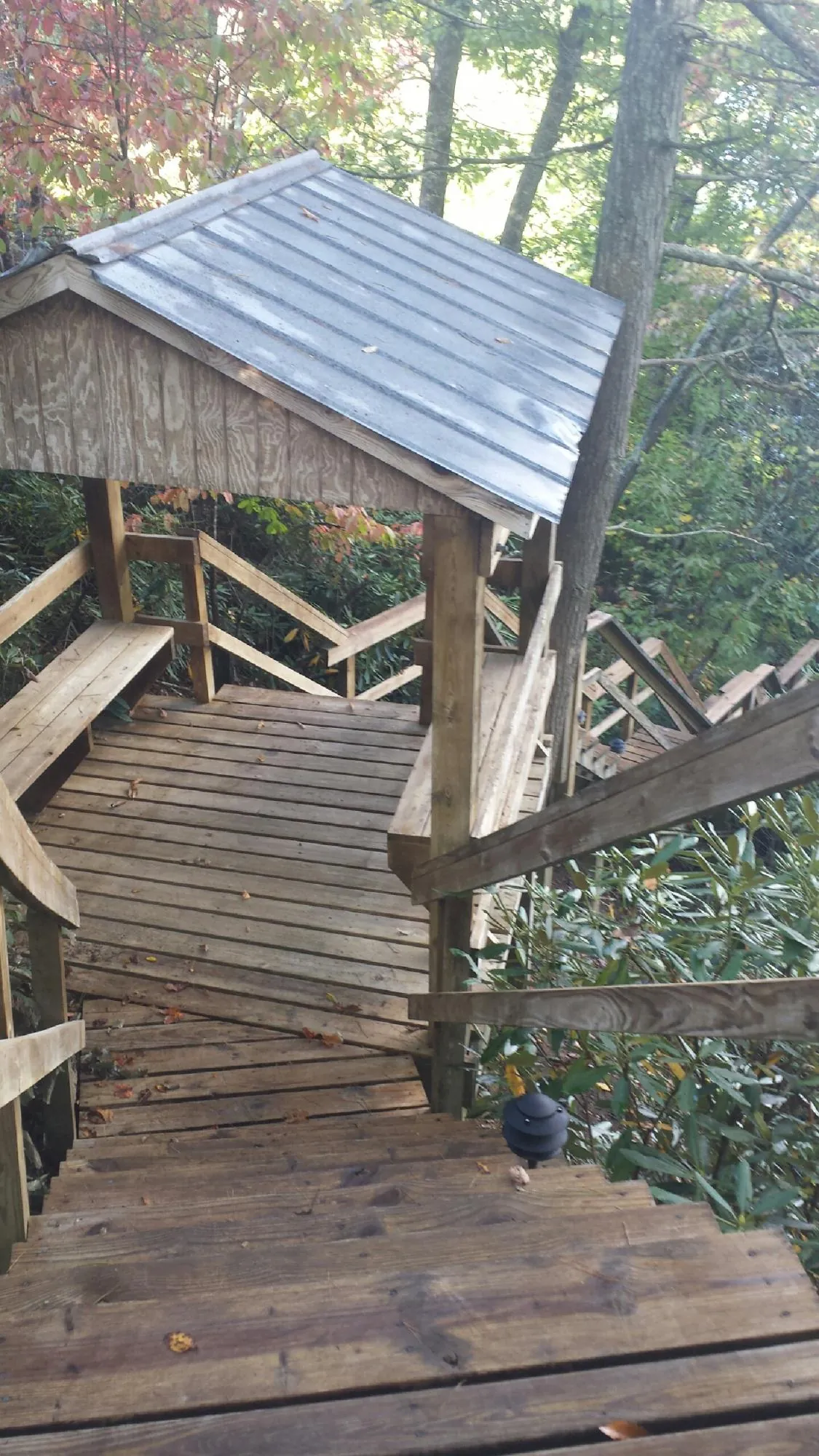 Metal roofed shelter over wooden steps on a wooded walkway — Skylight Repair & Installation work by our crew in Spotswood