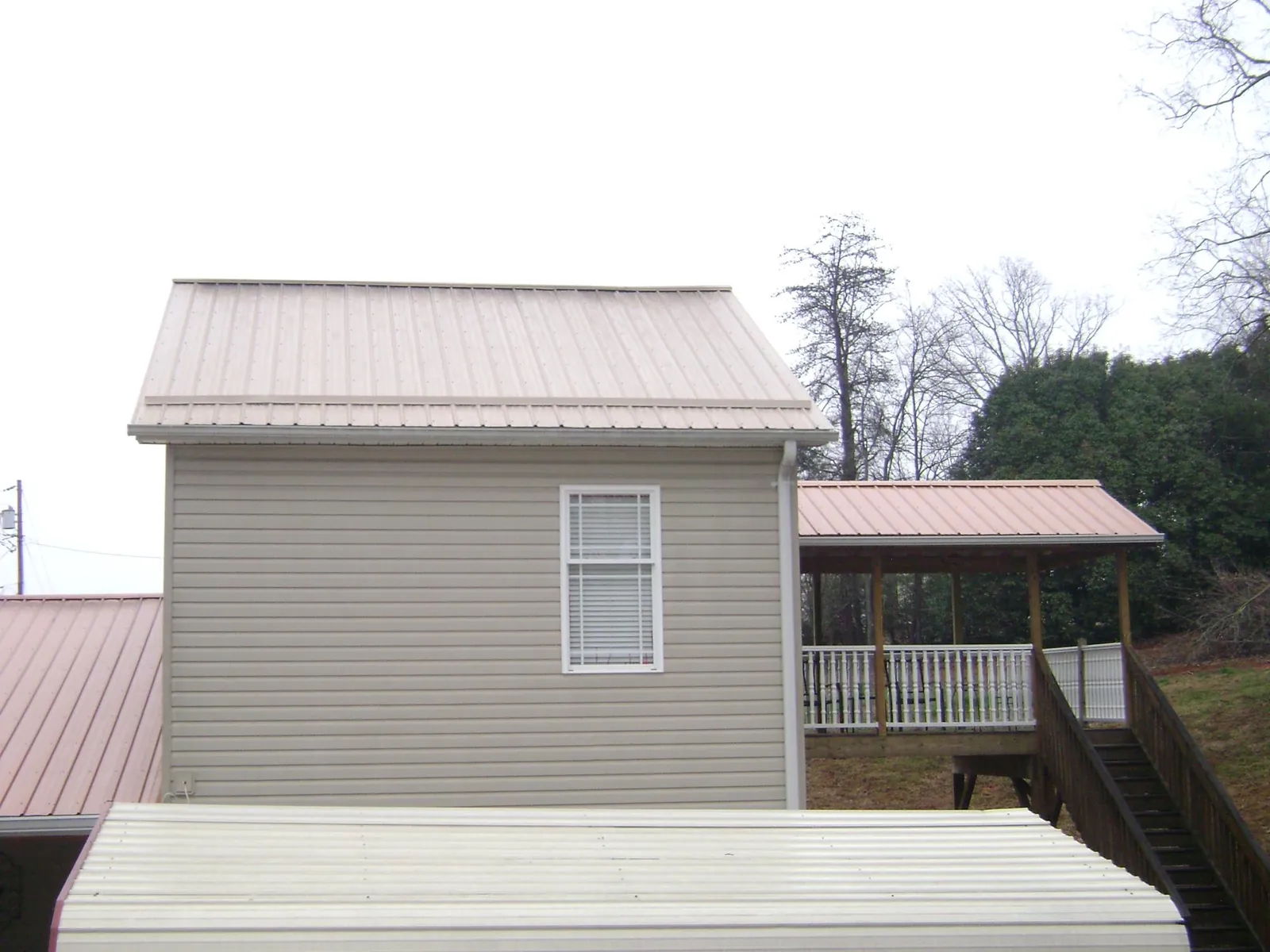 Tan metal roofs on a two story addition and attached porch, from a Roof Replacement job in Spotswood