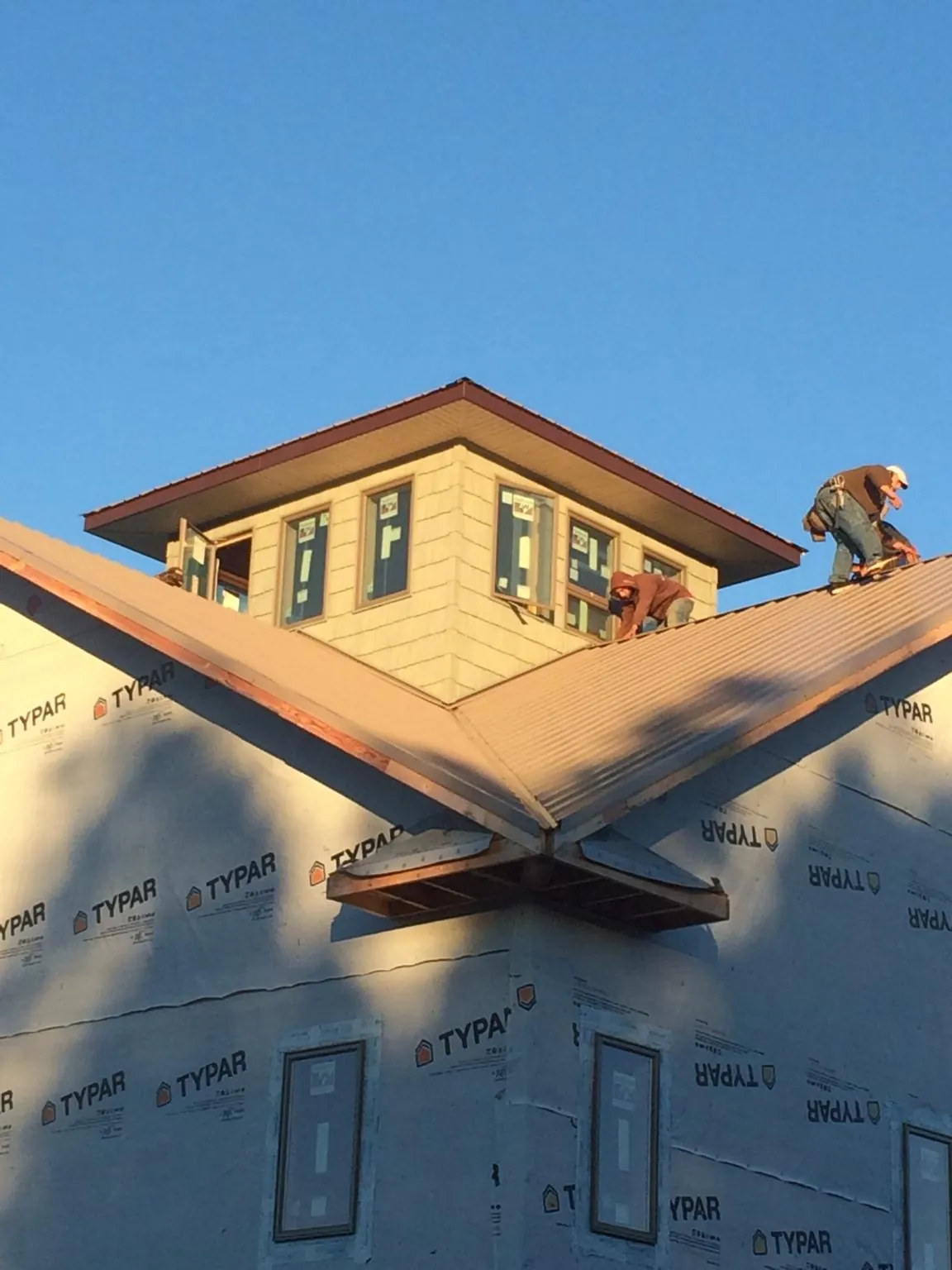 Roofers working around a rooftop cupola on a new metal roof at sunset — Roof Waterproofing in Spotswood by Roofing Brothers